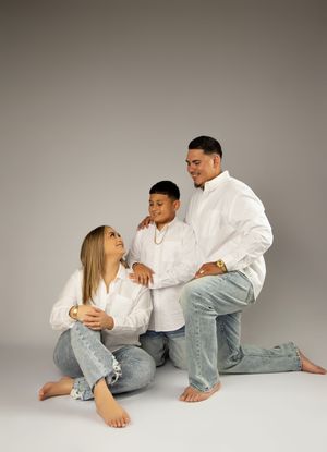 Intimate family photo session with casual white shirts and jeans against neutral backdrop.