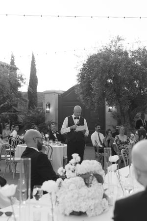 An outdoor wedding reception table setting decorated with white floral centerpieces in a garden venue.