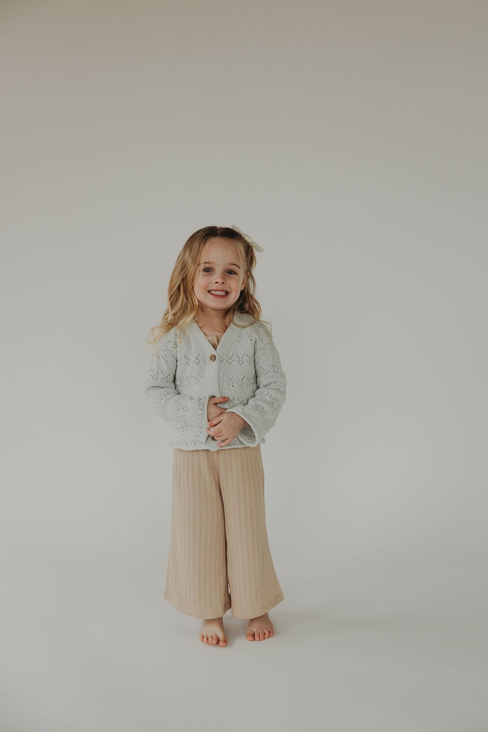 A collection of photos showing someone wearing a grey knit sweater with beige wide-leg pants against a light background.