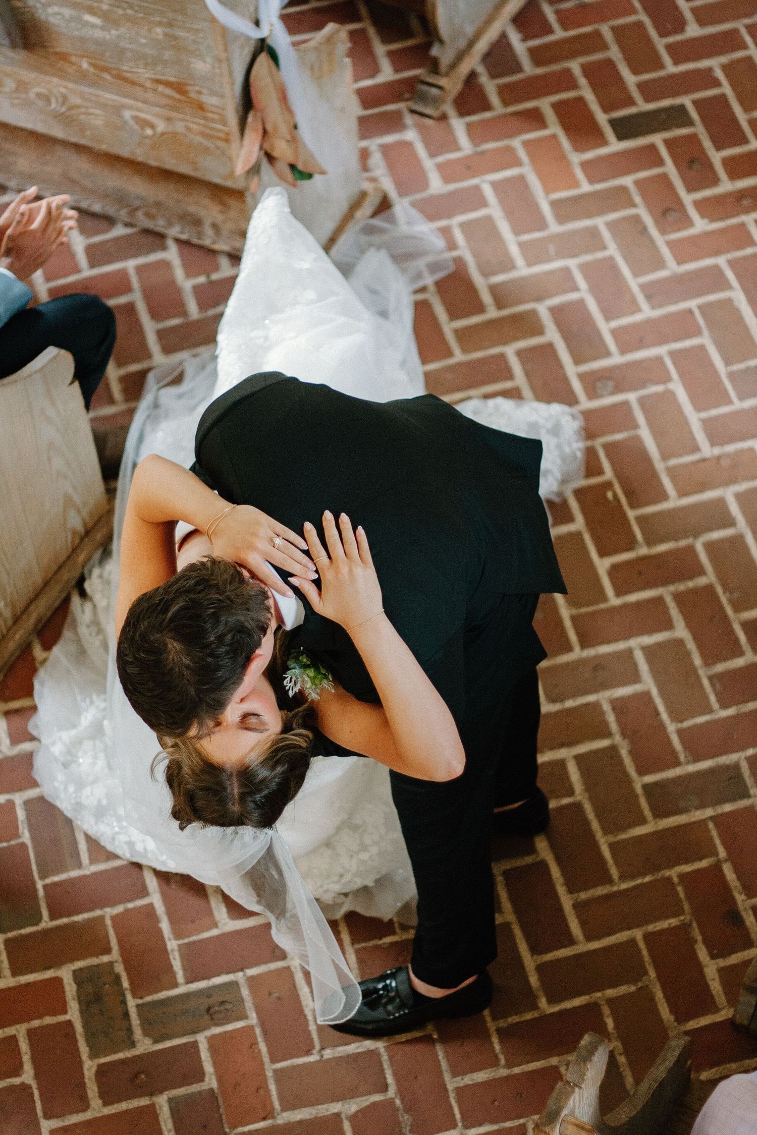 Aerial view of a couple dancing on a brick floor with the bride wearing a black dress and white veil.