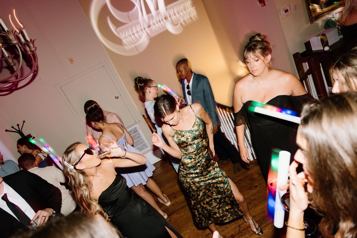 A group of people dancing and celebrating at a festive party with colored lights and music.