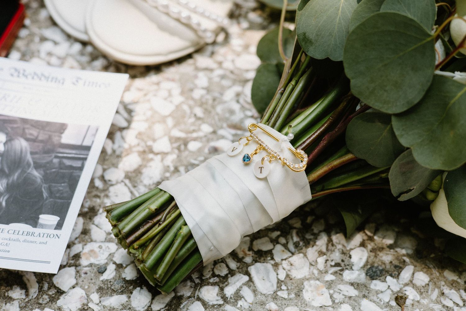 Wedding bouquet wrapped in white ribbon with wedding rings and a vintage photograph on lace background.