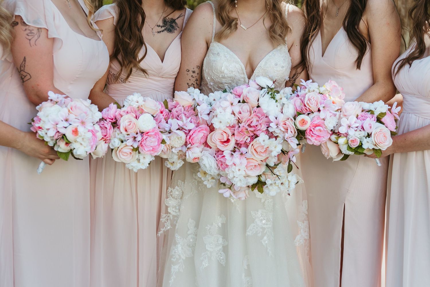 Row of pink and white wedding bouquets held by bridesmaids in matching dresses.