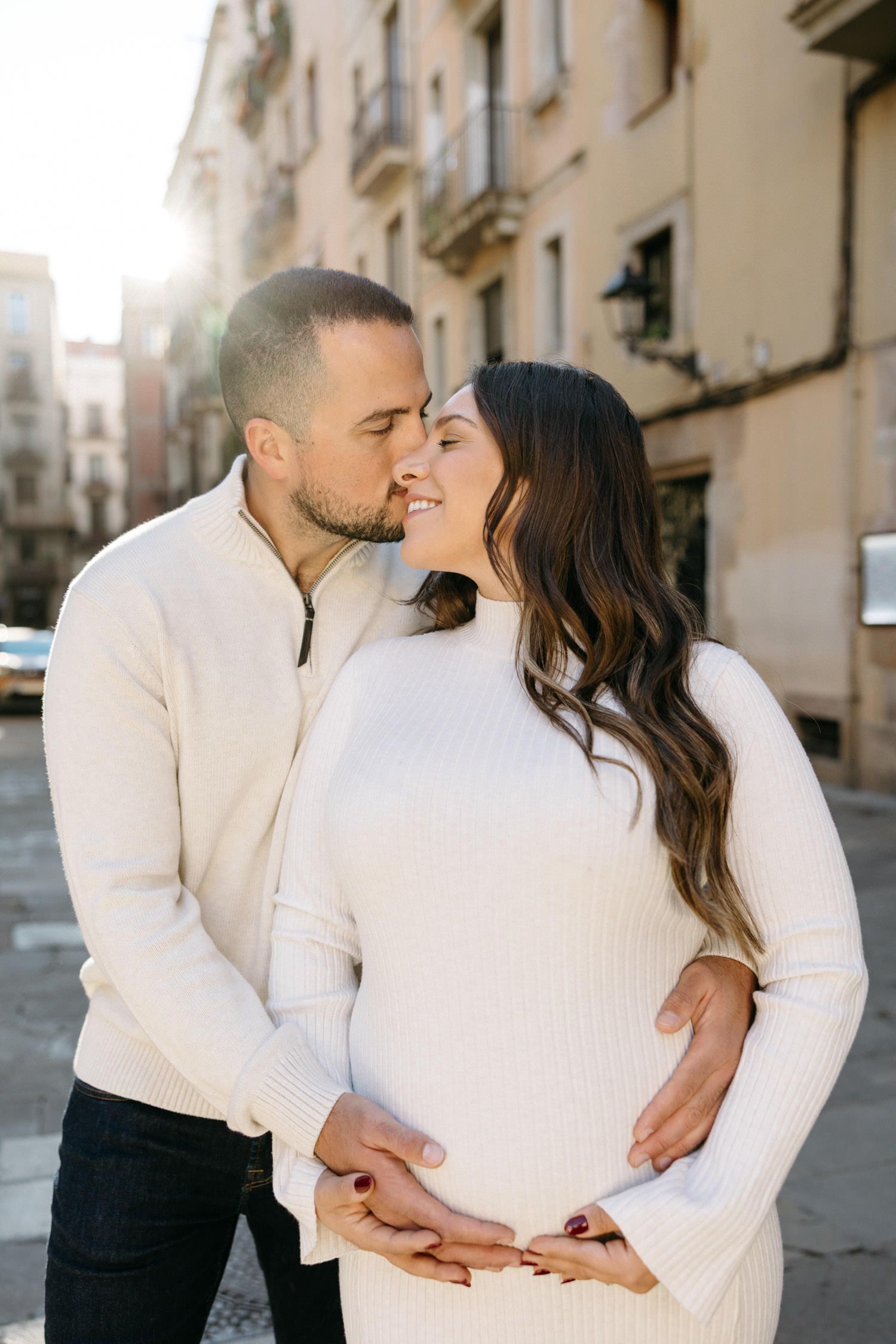 Intimate maternity portraits against warm stone buildings in European city street.