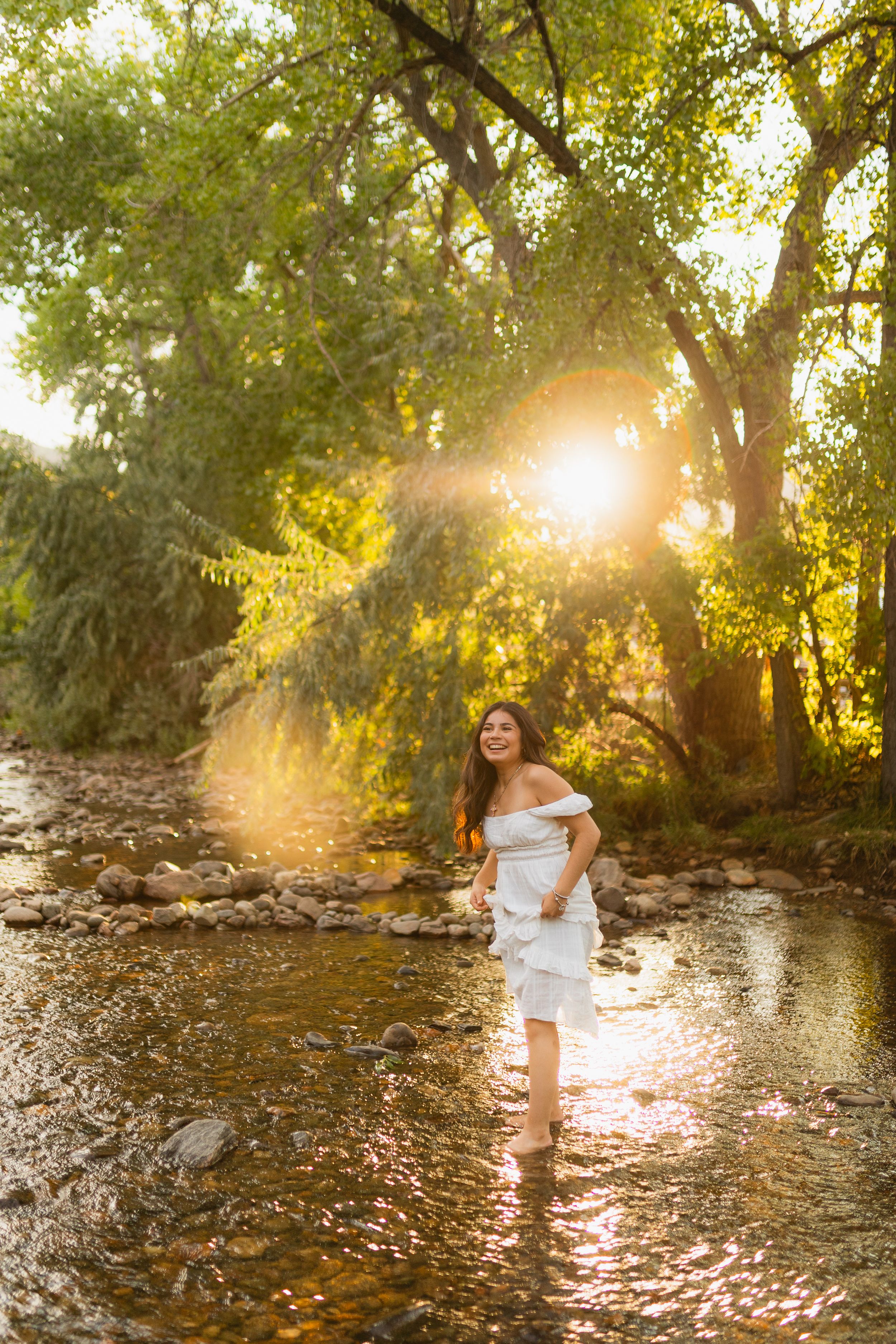 Beautiful photoshoot in a tranquil creek with sunlight filtering through trees creating dreamy golden hour ambiance.
