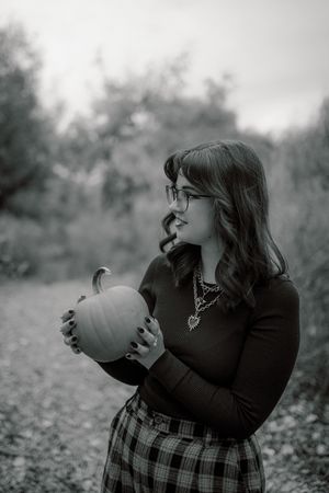 A sequence of black and white photos shows a person in plaid skirt blowing up a balloon in a meadow.