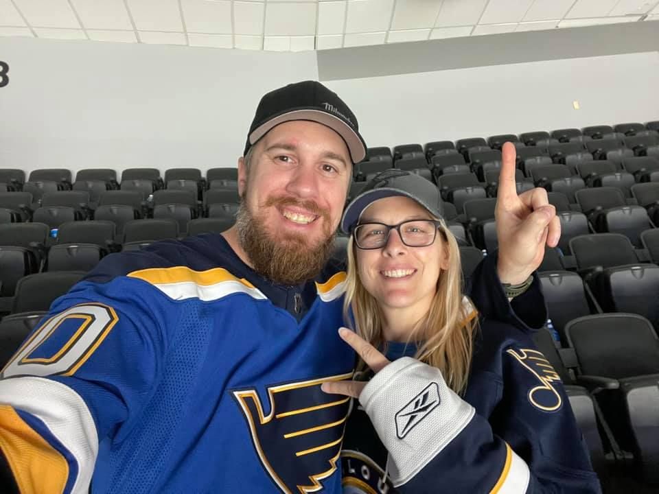 Portrait of man and women wearing St. Louis Blues jerseys and hats.