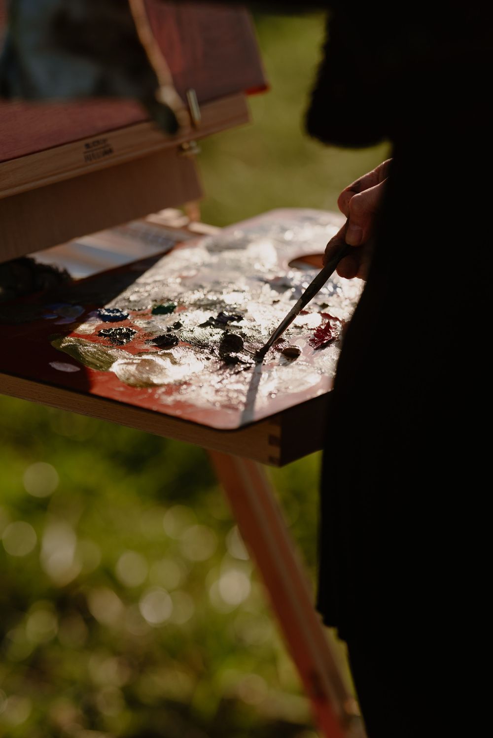 Artist's palette with paint colors being mixed during an outdoor event.