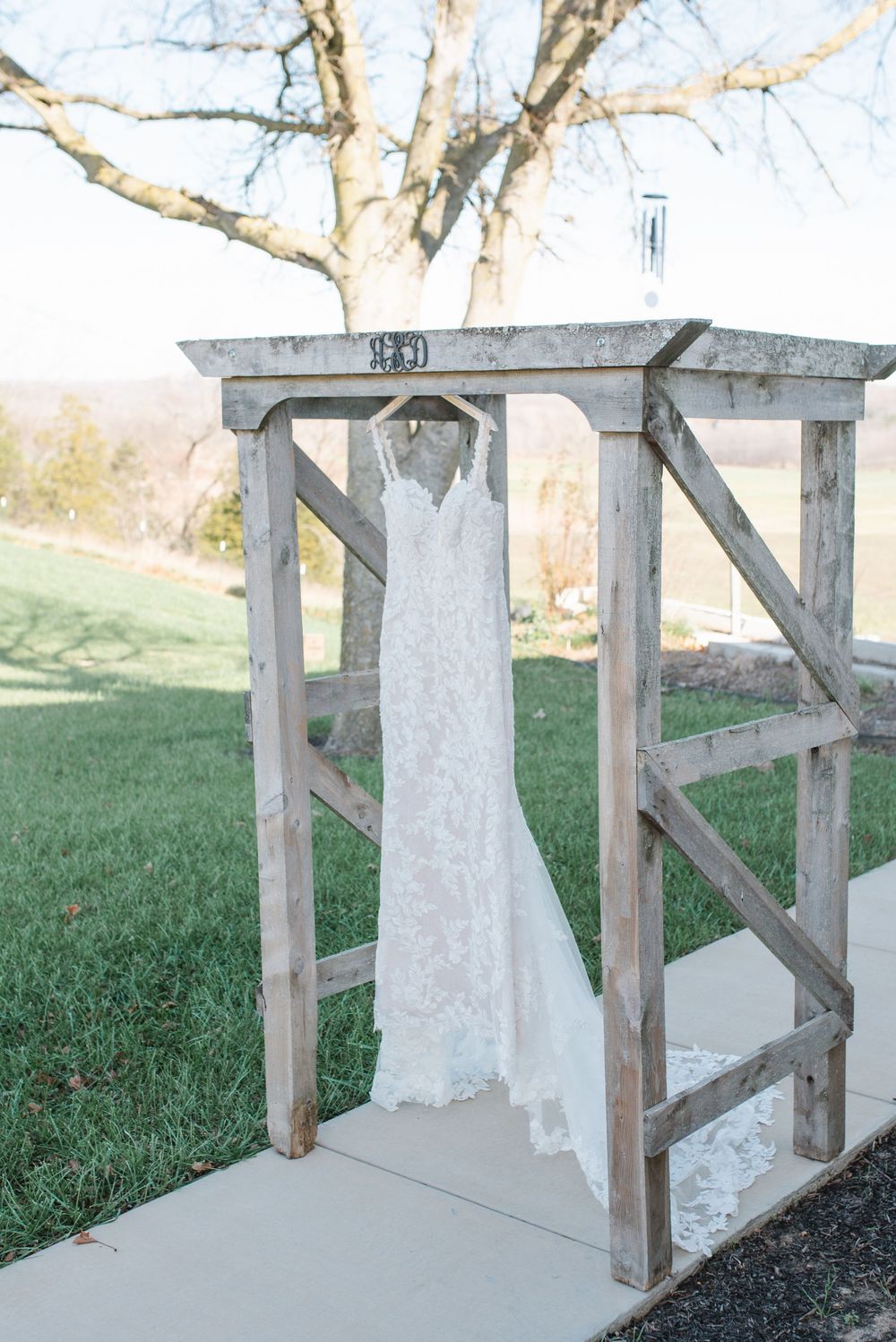 An elegant white wedding gown displayed on a weathered wooden arbor structure.
