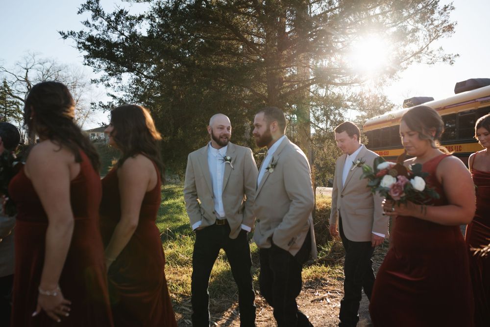 Wedding party members gathered outdoors during sunset in casual conversation.