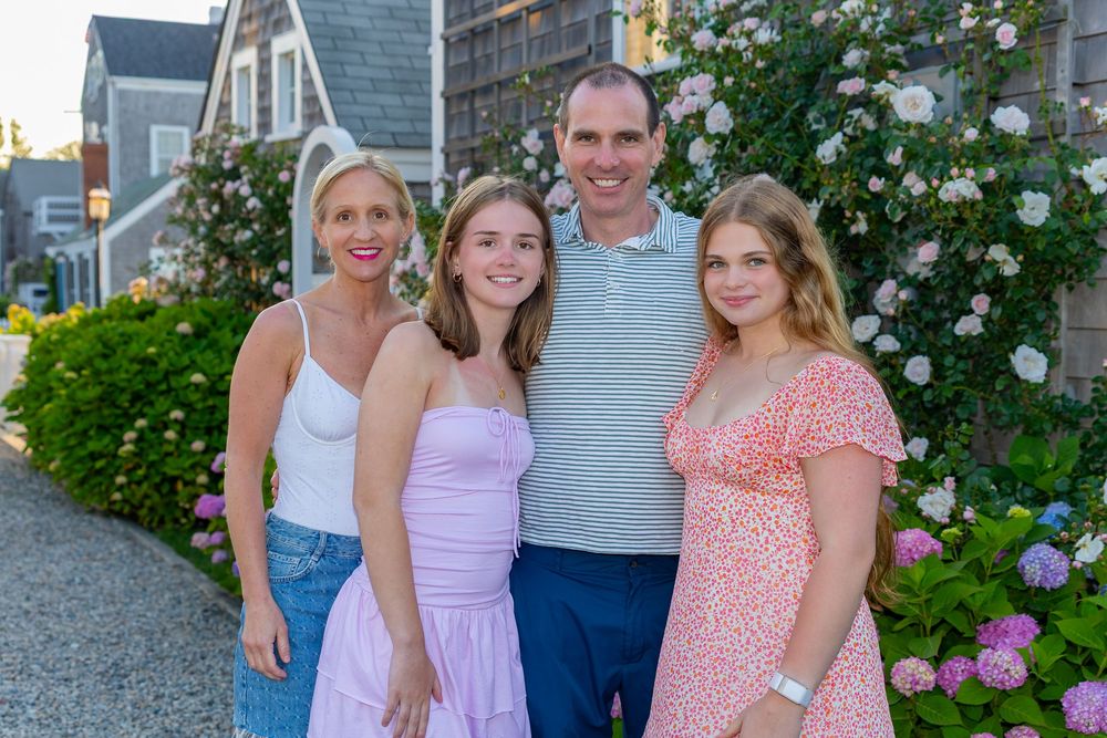 A family poses together on Old North Wharf in front of blooming rose bushes on a summer evening on Nantucket, MA by Lisa West Photography.
