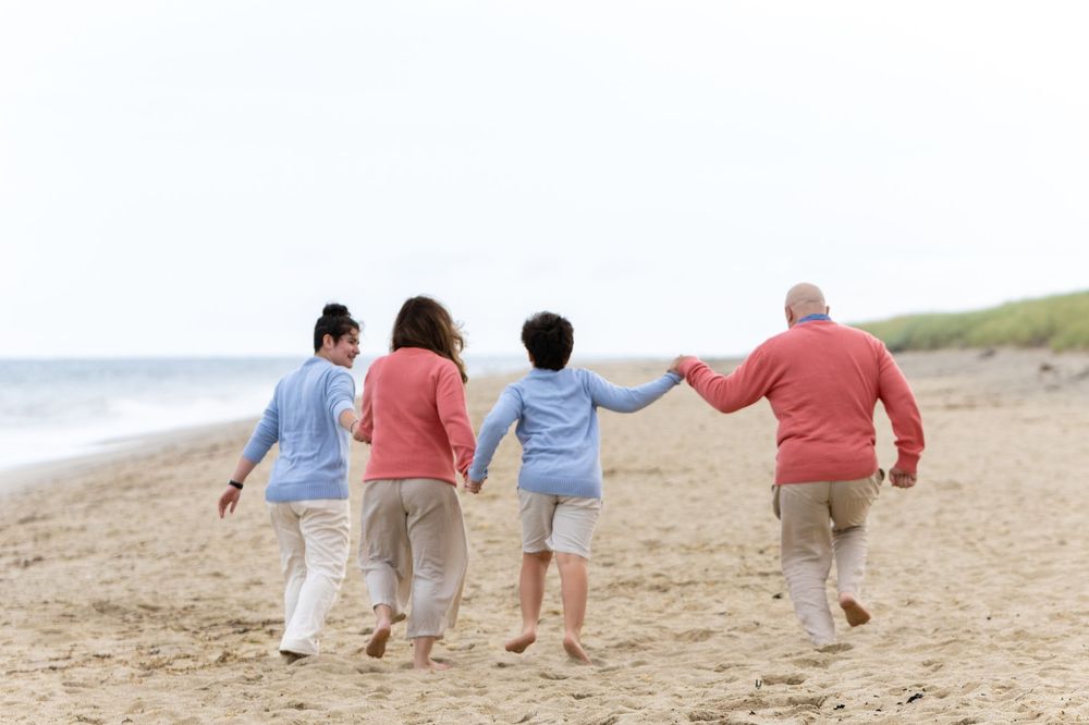 Family walking hand in hand while enjoying a sunny day together on a sandy beach near the ocean at Low Beach on Nantucket, MA (Sconset).