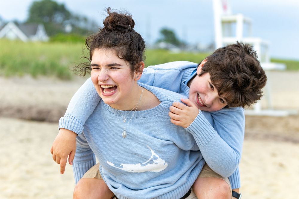 Siblings laughing together at a family portrait session at Low Beach on Nantucket, MA (Sconset) by Lisa West Photography