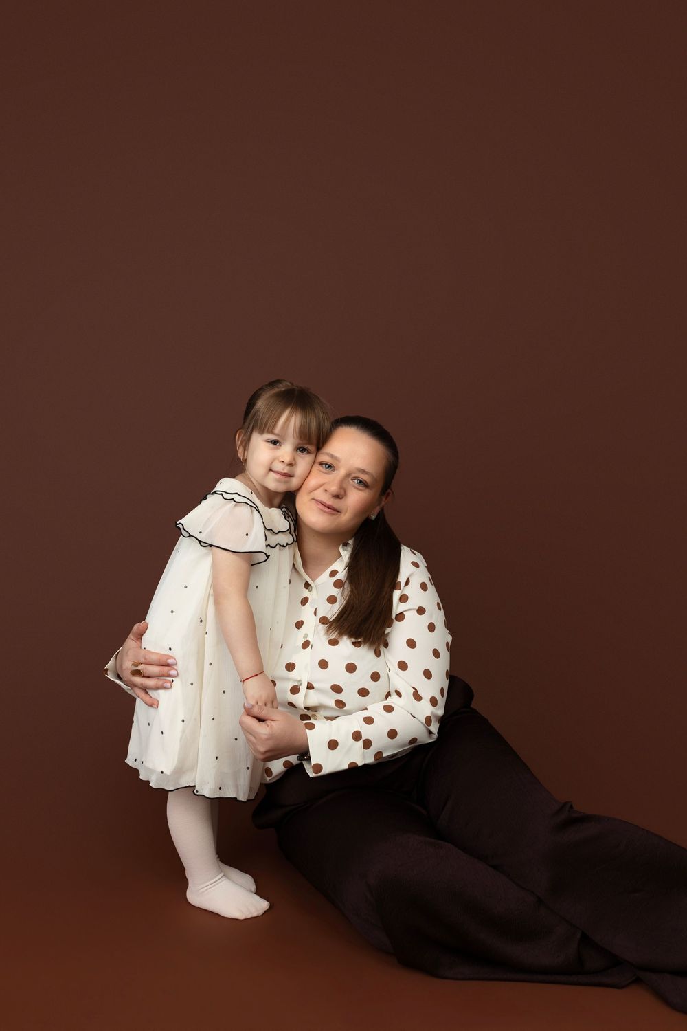A series of intimate family portrait photos showing tender moments between parent and child against a brown background.
