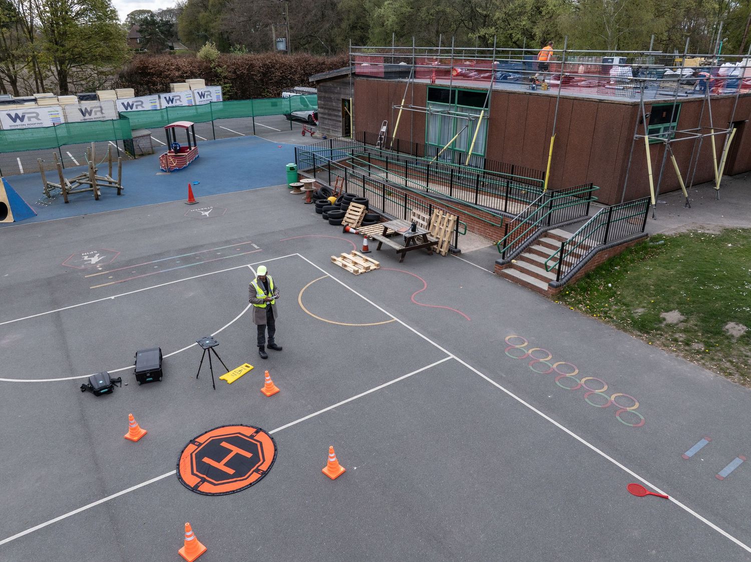 Children's playground area with basketball court and colorful safety markings on blue rubber surface.