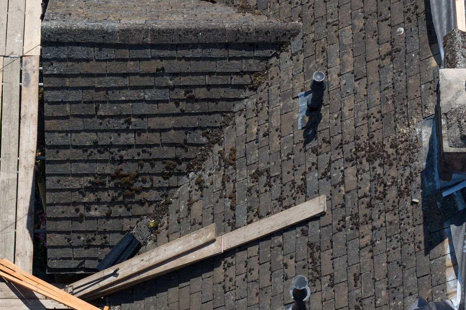 Aerial view of construction materials and wooden planks laid out along a dark brick wall.