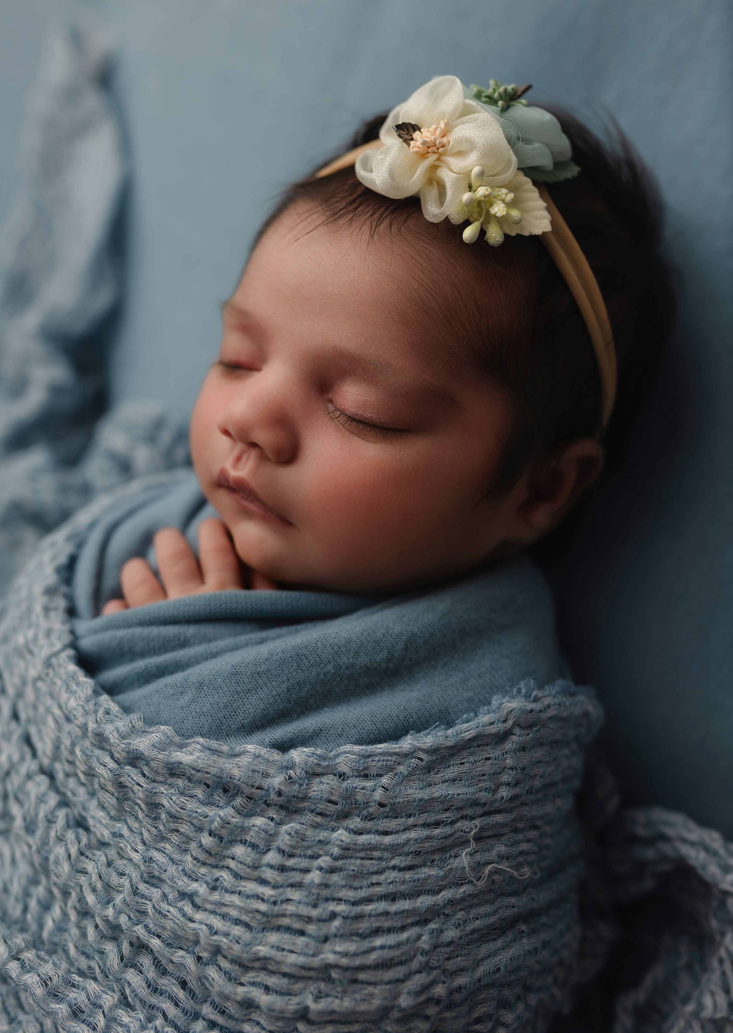Detailed studio portrait of a sleeping newborn girl on a blue blanket, showing her eyelashes and peaceful expression – Charlottesville, VA.