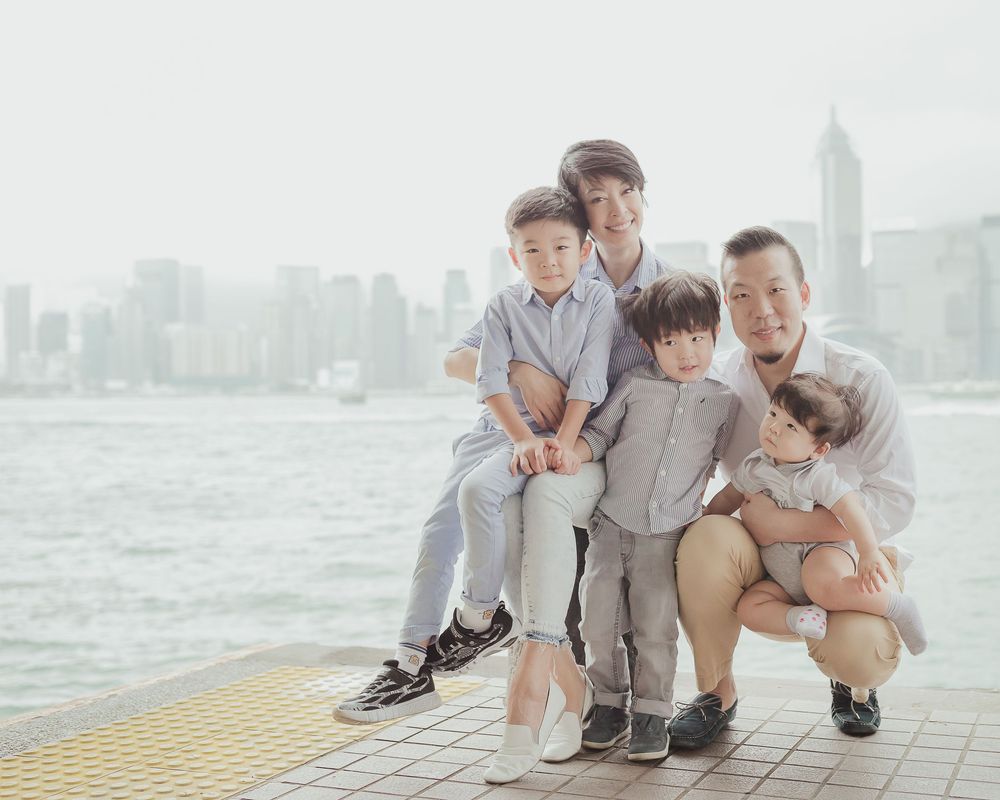 Group poses together on urban waterfront walkway with city skyline in background and warm evening light.