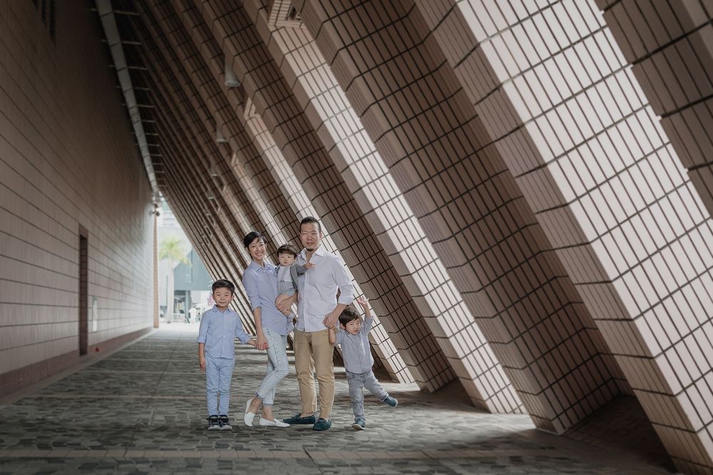 Two people in light blue casual attire walking down an angular urban architectural corridor.