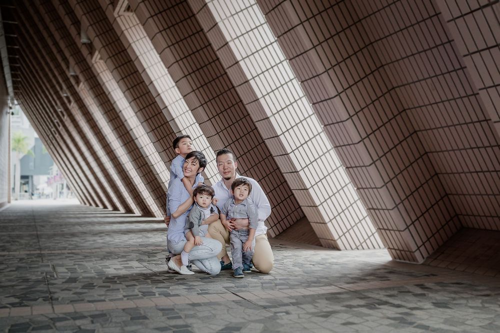 People pose in front of a geometric concrete structure with angled walls creating a dramatic architectural perspective.
