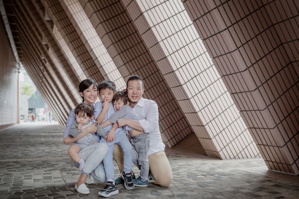 A family poses together under a modern architectural structure with geometric patterns and natural lighting.