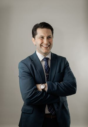 Professional headshots of someone in a navy suit and striped tie against a neutral backdrop showing various poses and expressions.