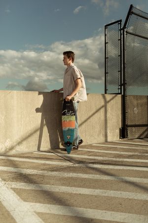 A person walks up concrete steps next to a chain link fence casting dramatic diagonal shadows in sunlight.
