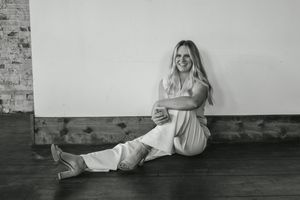 A series of black and white maternity photos showing a pregnant woman in flowing dress against a rustic wall background.