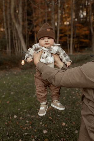 A sequence of playful outdoor photos showing someone being swung around in brown clothing against an autumn forest backdrop.