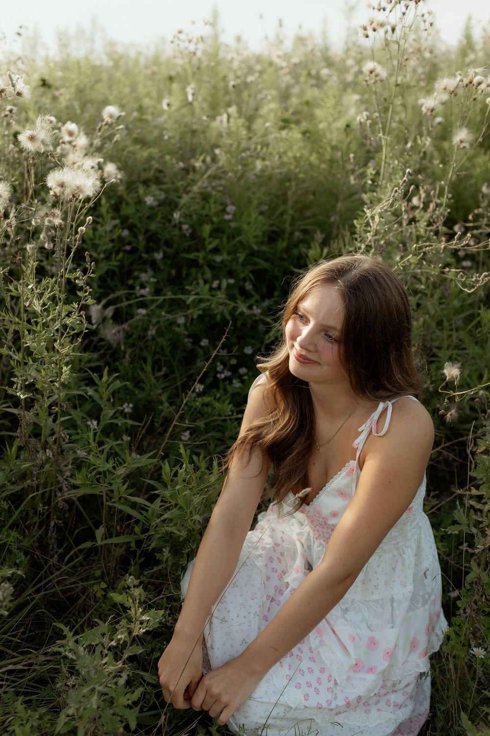 A dreamy outdoor portrait series in white floral dresses against lush green foliage creates an ethereal summer mood.
