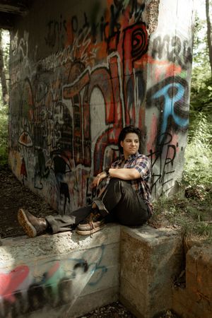 Graffiti-covered concrete walls in an abandoned urban setting with natural light filtering through trees.