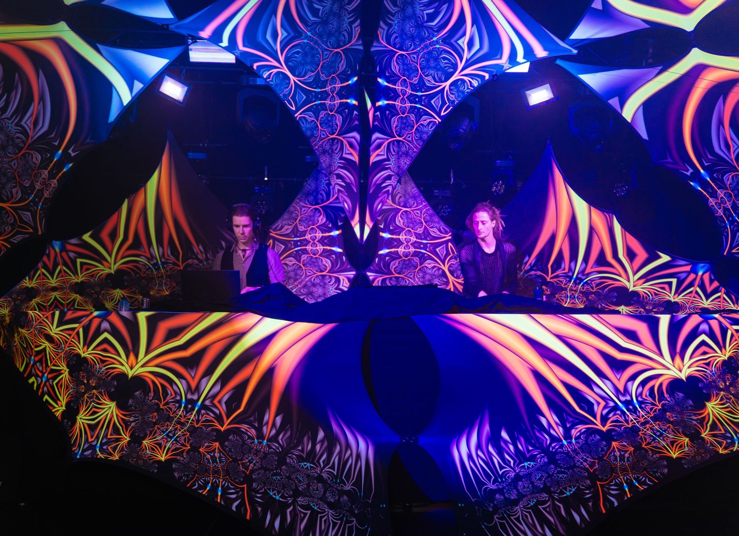 Intense blue and purple lighting illuminating complex, abstract ceiling decorations at a psy-rave event. Drops Festival Netherlands vivitu
