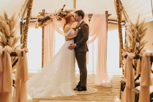 A wedding ceremony unfolds at Nuddock Wood Lake, with natural light streaming through windows illuminating the moment.