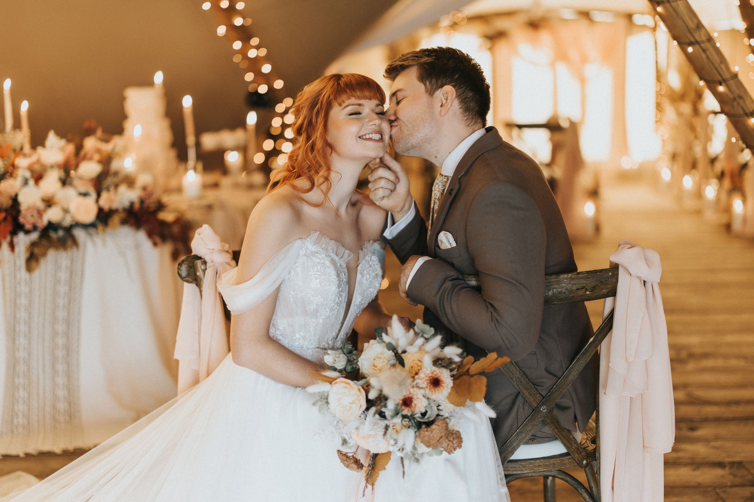 A romantic wedding couple shares an intimate moment at Nuddock Wood Lake with warm lighting and floral arrangements.