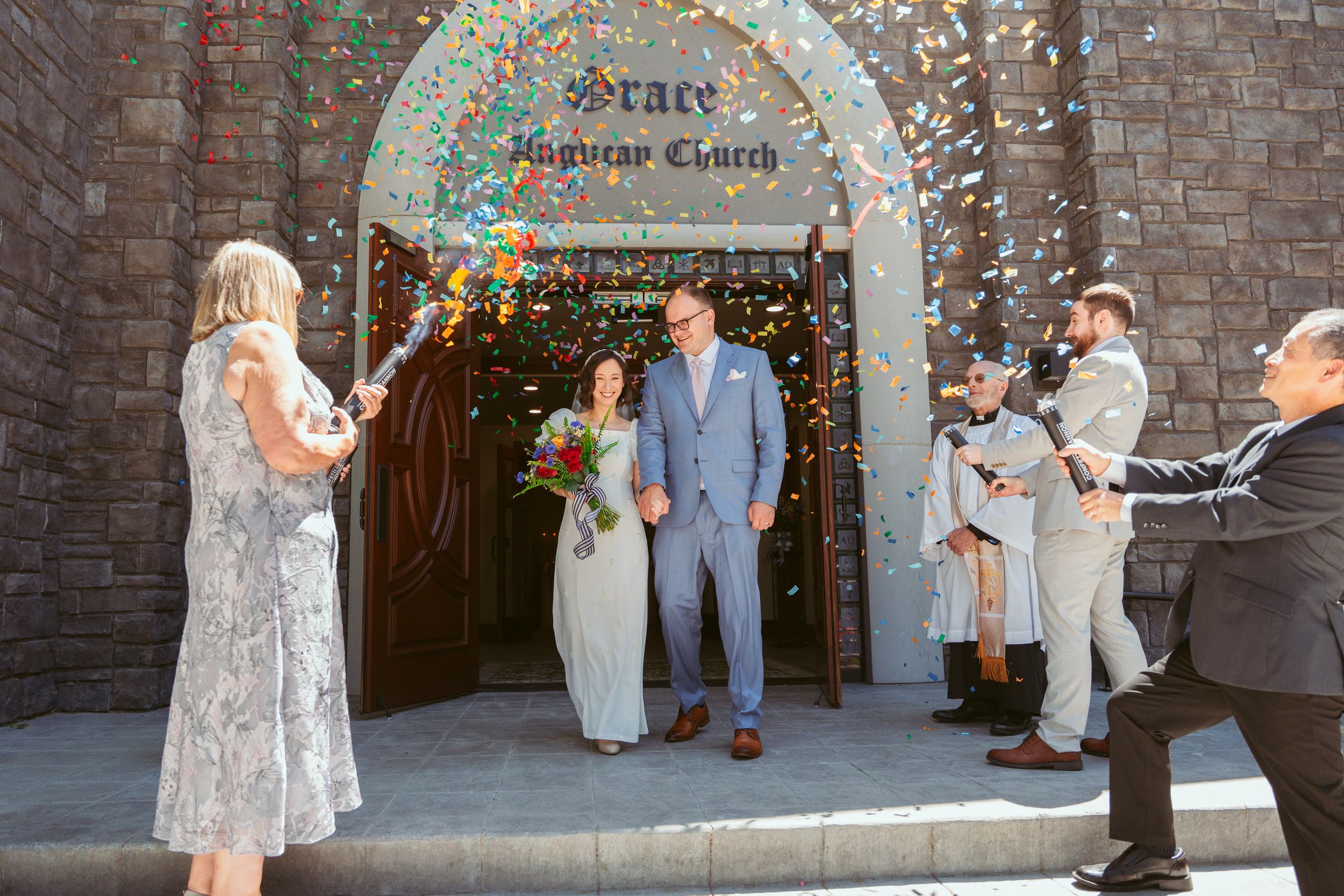Couple exchanges wedding vows during outdoor ceremony at church entrance with stone walls and autumn decorations.