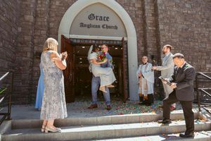 People gather outside a vintage brick church entrance during a casual celebration moment in natural daylight.