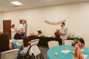 A series of people sitting at tables participating in a team building workshop or training session in an office meeting room.