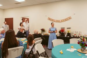 Wedding shower party setup with blue-green tablecloths and decorations in a bright indoor event space.