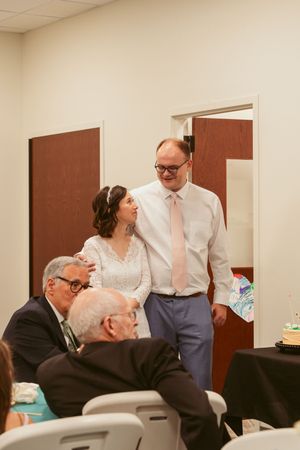 Couple stands with wedding guests at a reception while wearing formal attire and enjoying conversation.