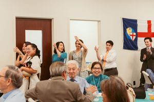 Group of business professionals gesture enthusiastically during a corporate meeting in a bright conference room.