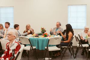 A series of images showing a social gathering with round tables decorated in blue tablecloths in a community room.