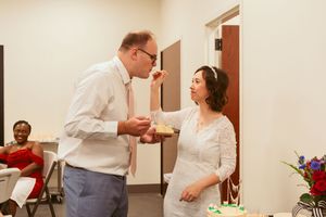 Two people share a lively conversation at an indoor event decorated with floral arrangements.