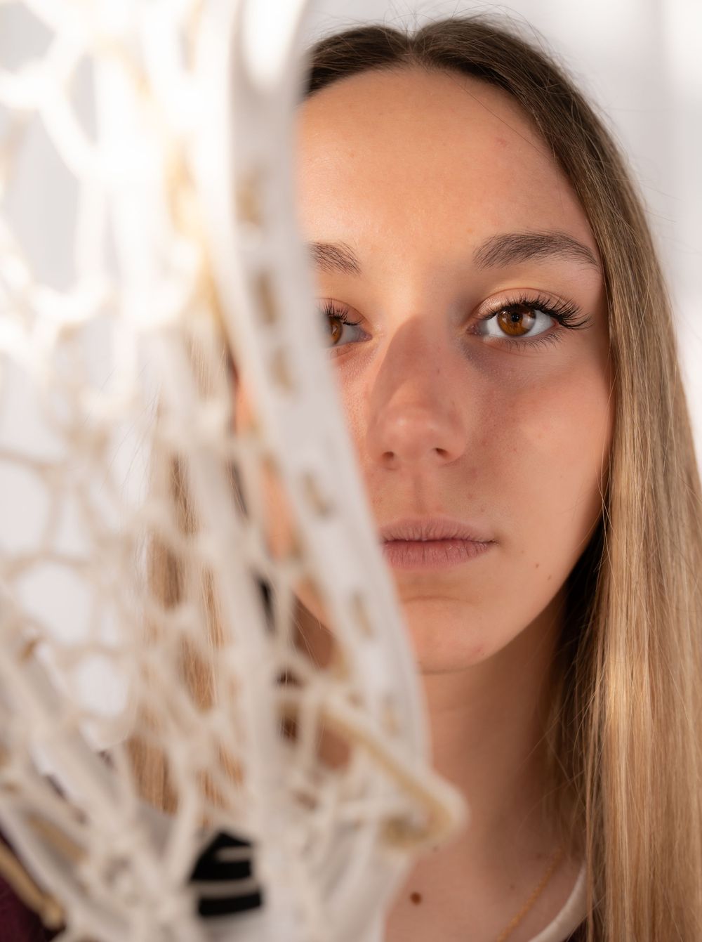 Artistic portrait shot through white textured material creating a dreamy effect. High School athlete media day photo shoot