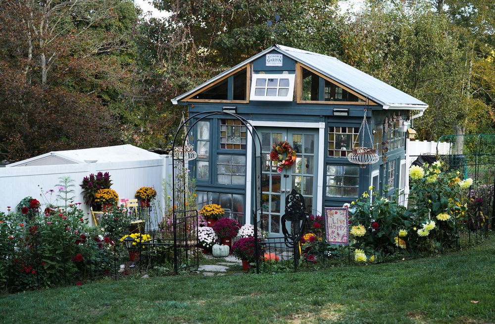 Charming blue garden shed decorated with autumn flowers and wreaths.