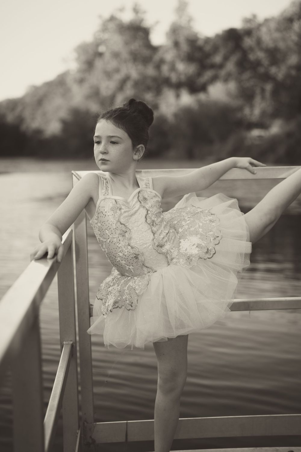 Black and white photo of dancer striking elegant pose on waterfront dock.