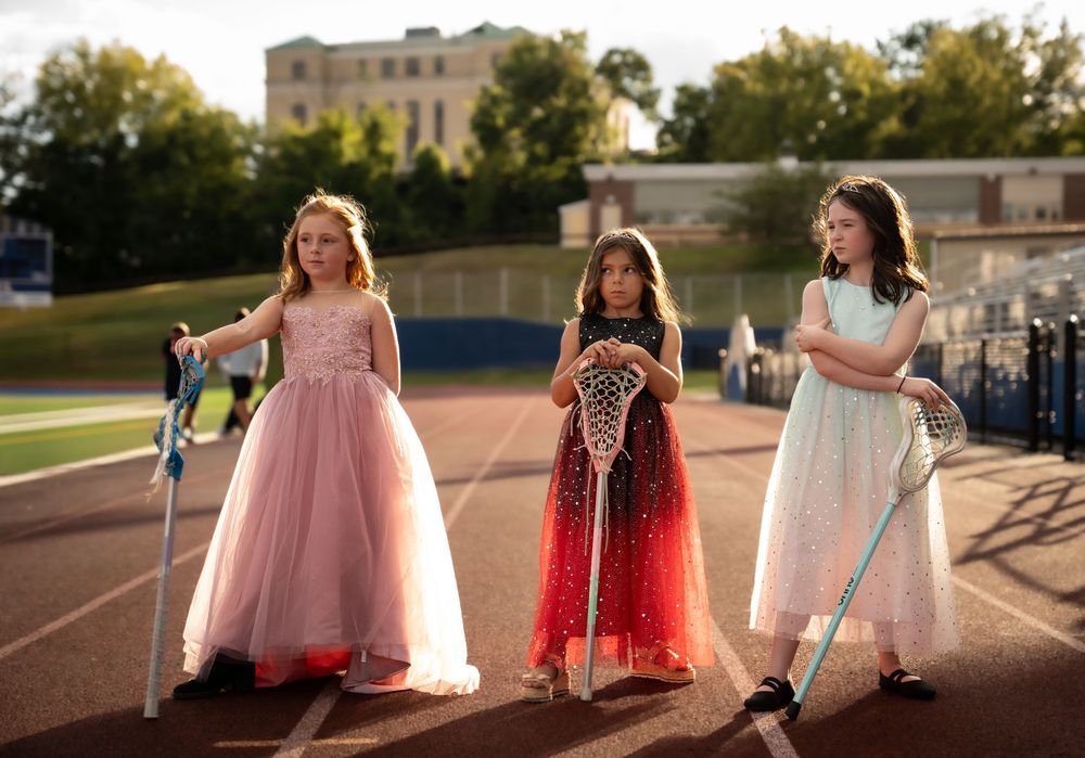 Group in formal dresses creates dreamy silhouettes at sunset on outdoor track.