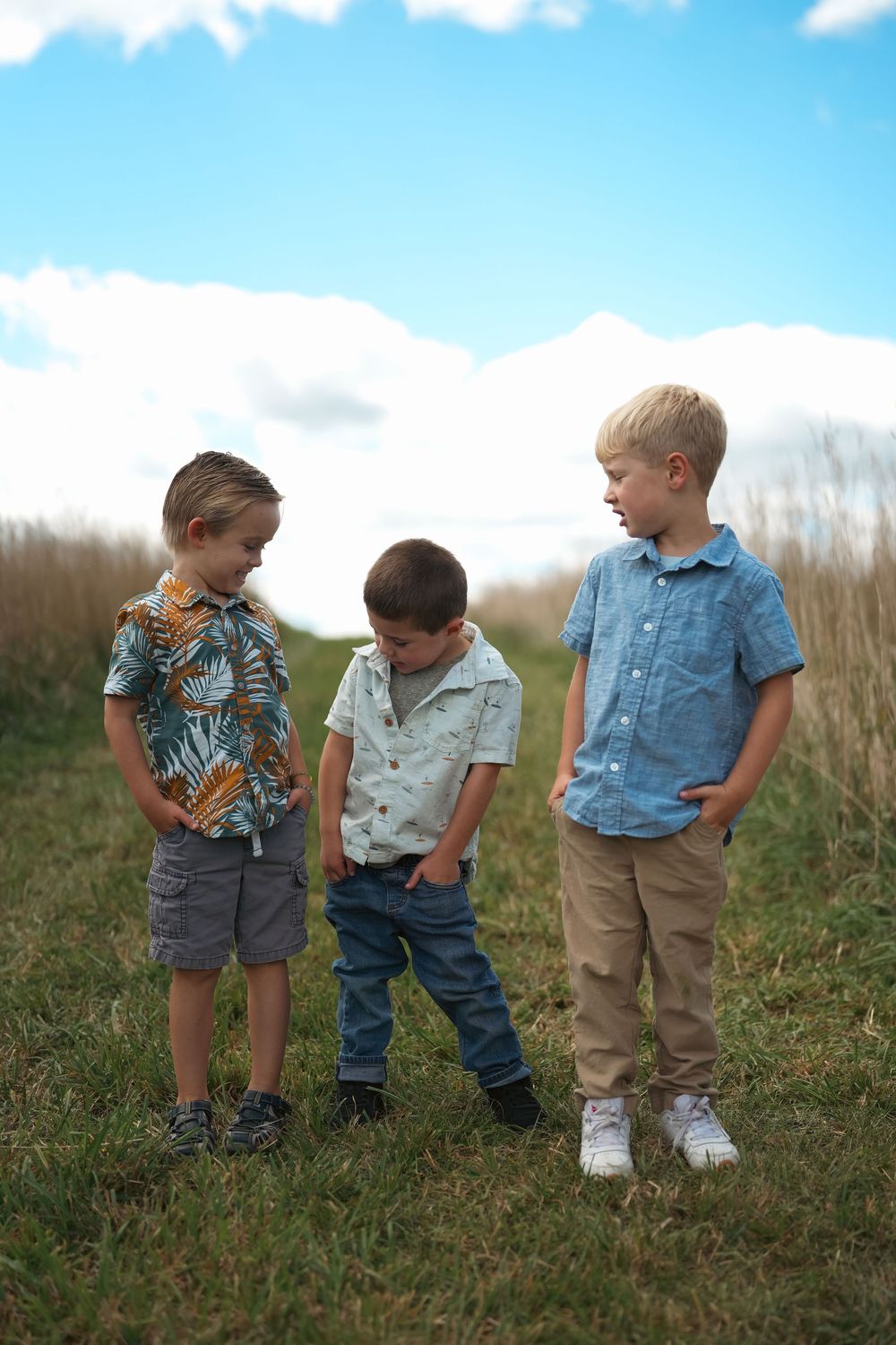 Young children in casual clothes stand together on a grassy hillside.