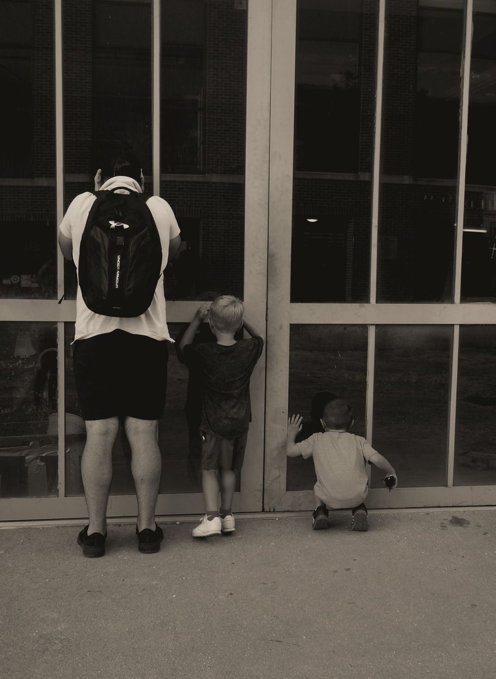 Black and white photo showing legs of people standing outside a building entrance.