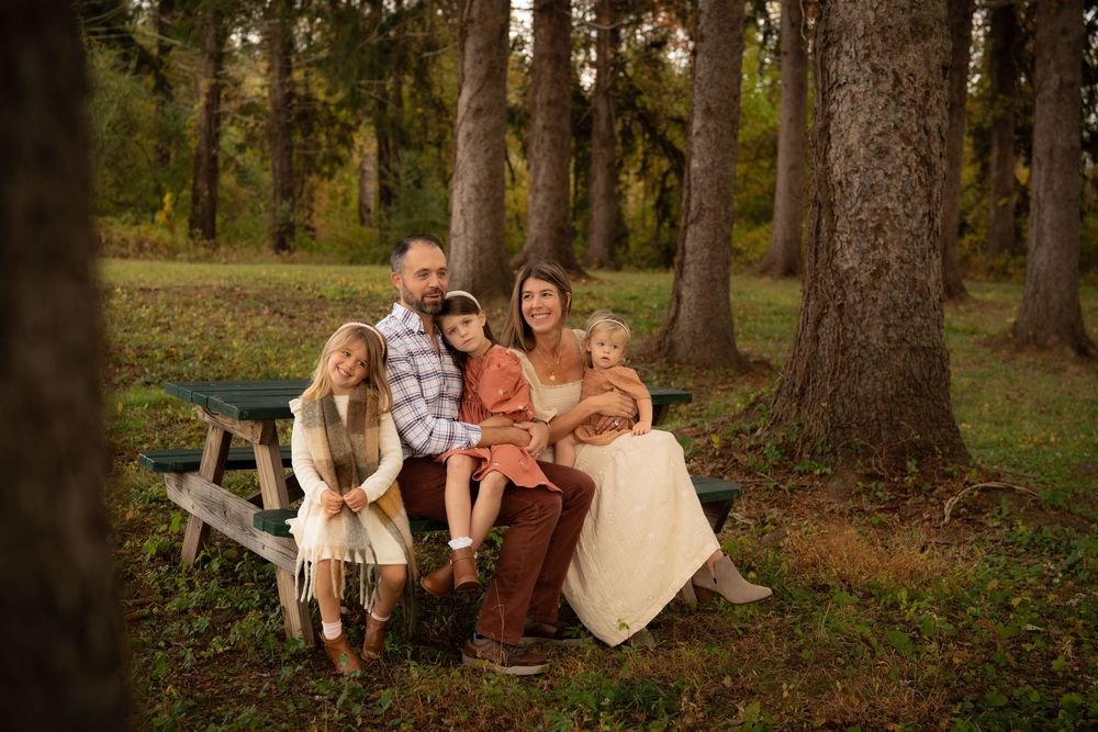 A family poses for photos in a wooded setting during fall.