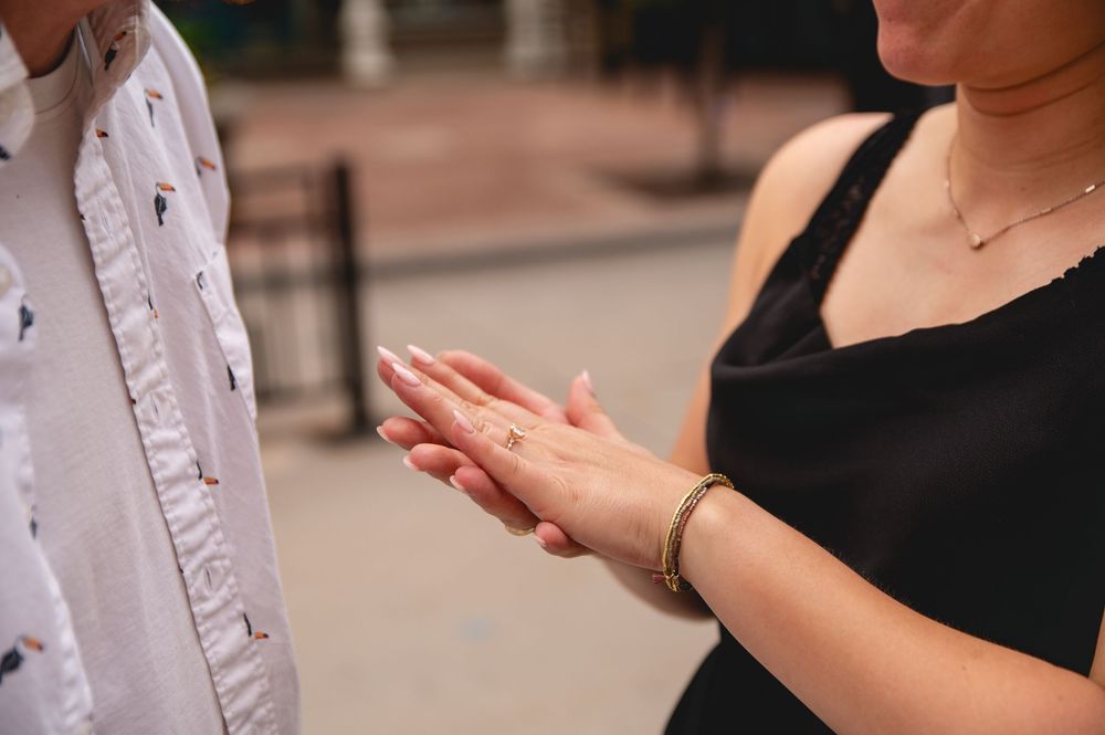 A person holds and inspects a piece of jewelry against a blurred background in natural lighting.